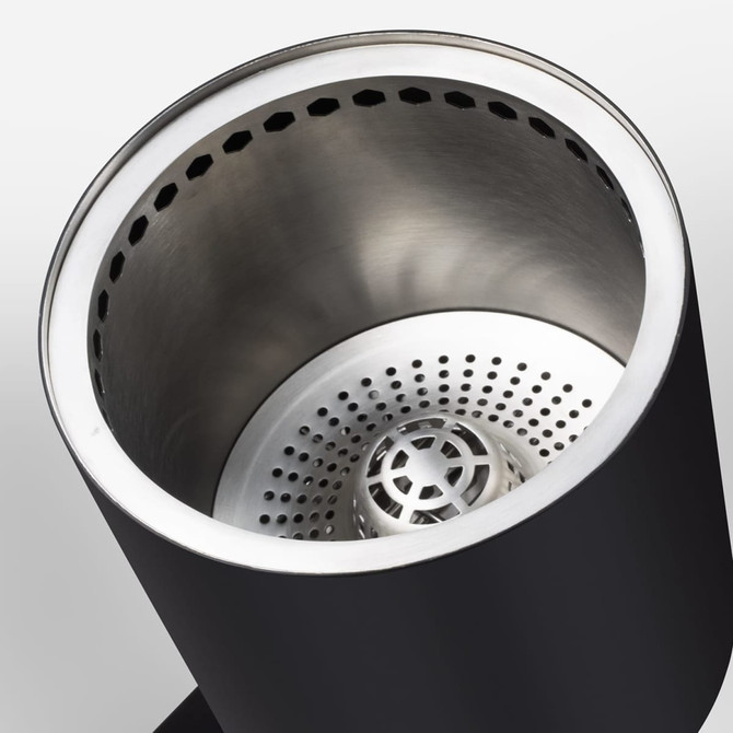 A cylindrical cooker with a black exterior and stainless steel interior, featuring perforations for ventilation.