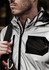 A reflective silver waterproof jacket with a black pocket, featuring a high collar and zip closure, worn by a model.