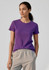 A purple women's short sleeve tee displayed on a model, paired with grey pants. The tee features a simple design and branding.
