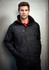 A man wearing a black unisex jacket with red accents and a zippered pocket, featuring a logo.