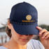 A navy trucker cap featuring a logo on the front and a decorative edge on the brim.