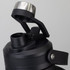 A drink bottle in black with a stainless steel lid and a removable cap, featuring a sturdy handle.