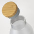 A drink bottle with a transparent body and a bamboo lid, featuring a grey seal.
