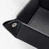 A black leather valet tray with stitched detailing and decorative fasteners at the corners.