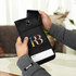 A black lockable phone pouch with a logo, being held with a smartphone partially inserted.