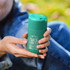 A drink bottle in a teal colour with a green lid, featuring mountain graphics and a logo.