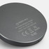 A circular grey wireless charger with a logo and output specifications on the base.