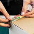 A person applies a colourful sticker featuring various designs to a brown cardboard box.