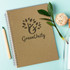 A medium Kraft notepad with a logo on the cover, placed beside a green pencil and decorative items on a light blue background.