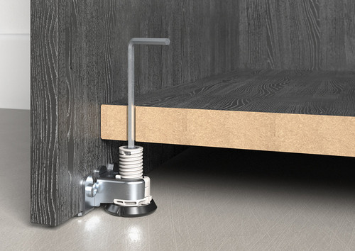 Heavy-duty adjustable furniture leg fitted beneath a cabinet base panel, allowing precise height adjustment and stable support for heavy furniture installations.