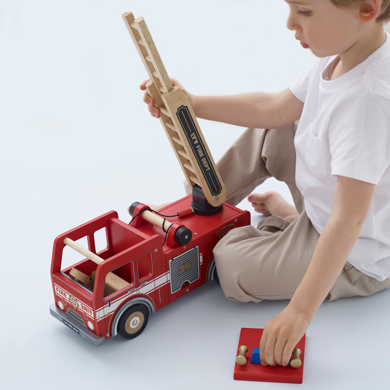 boy playing with le toy van fire truck