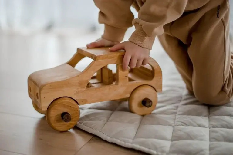child playing with wooden toy car