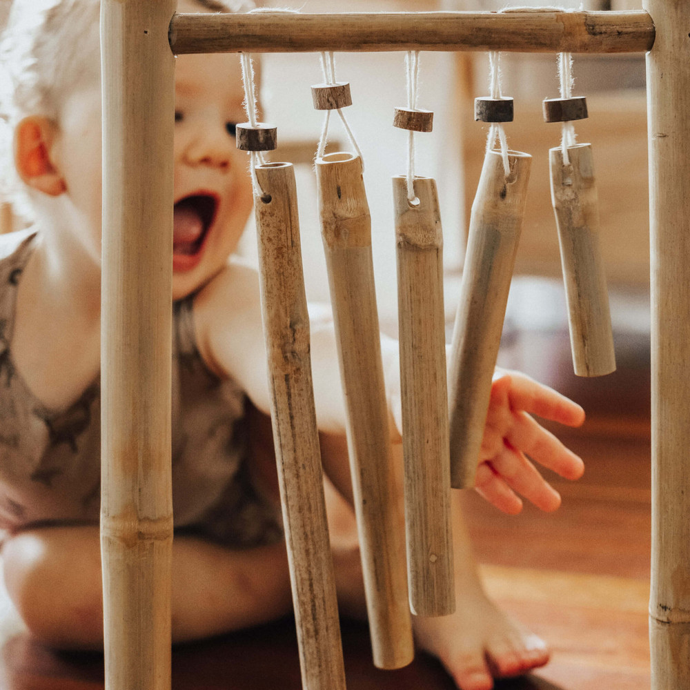 child playing with hanging bamboo xylophone