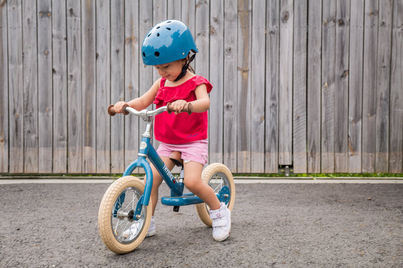 child on blue trybike with helmet