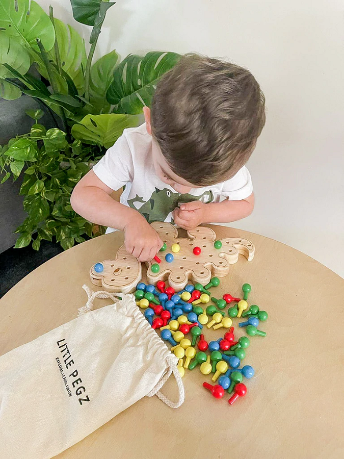 boy playing with little pegz dinosaur pegboard