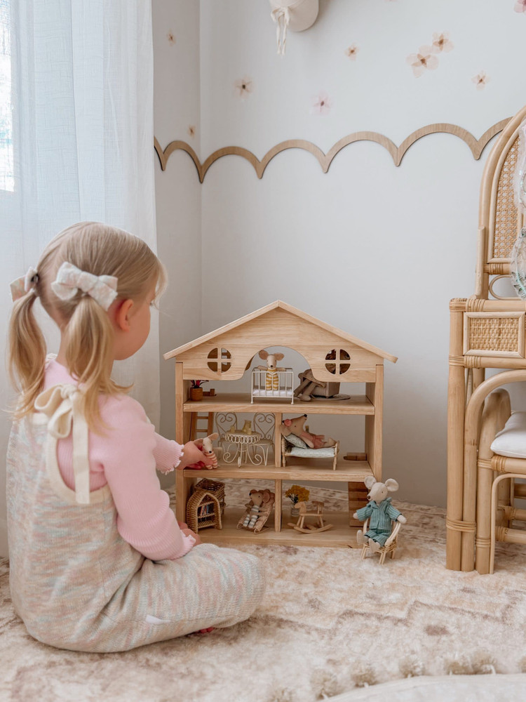 girl playing with classic wooden dollhouse
