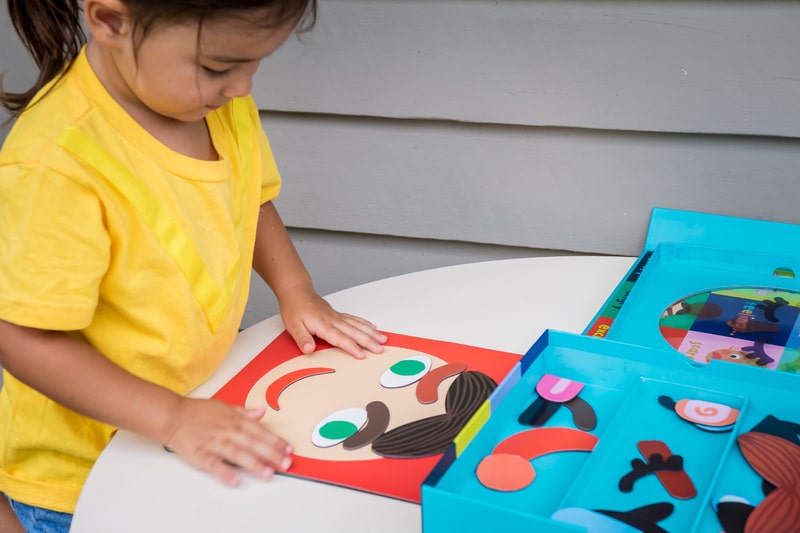 Child putting together a face with Manhattan Toy Making Faces Magnetic Set Child putting together a face with Manhattan Toy Making Faces Magnetic Set