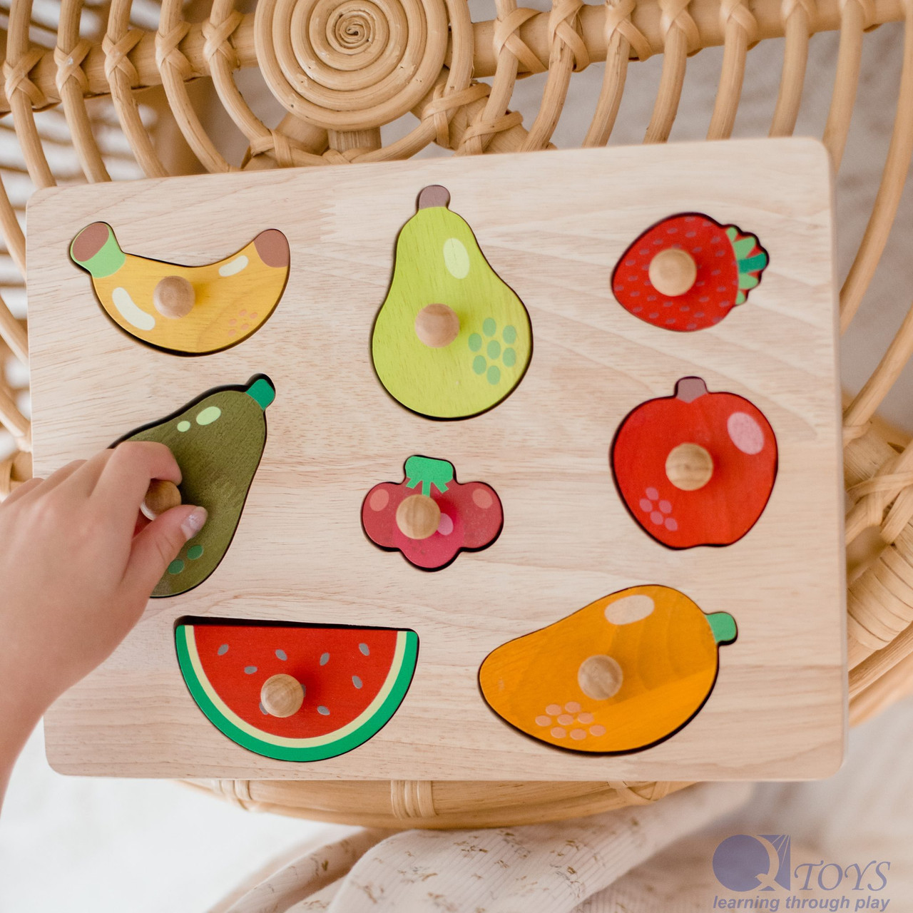 Qtoys Fruit Knob Puzzle with a child\'s hand grasping knob