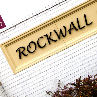 The city of Rockwall has, sitting beneath it, a row of hard mineral stones which appear to be stacked, long and narrow, forming what gives the impression of a rock wall.