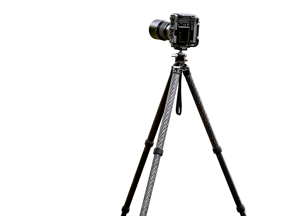 Outdoor landscape scene with Benchmark tripod at full height framing a horizon, inset showing a low-angle composition with legs splayed wide
