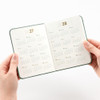 Hands holding a Hunter Green Making Memory Mini diary open to the 2027 and 2028 yearly calendar spread.