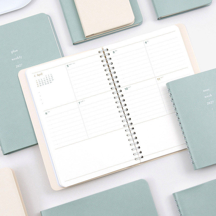 Byfulldesign 2027 Twin-Wire Weekly Planner with a clean April weekly spread surrounded by textured planner covers.