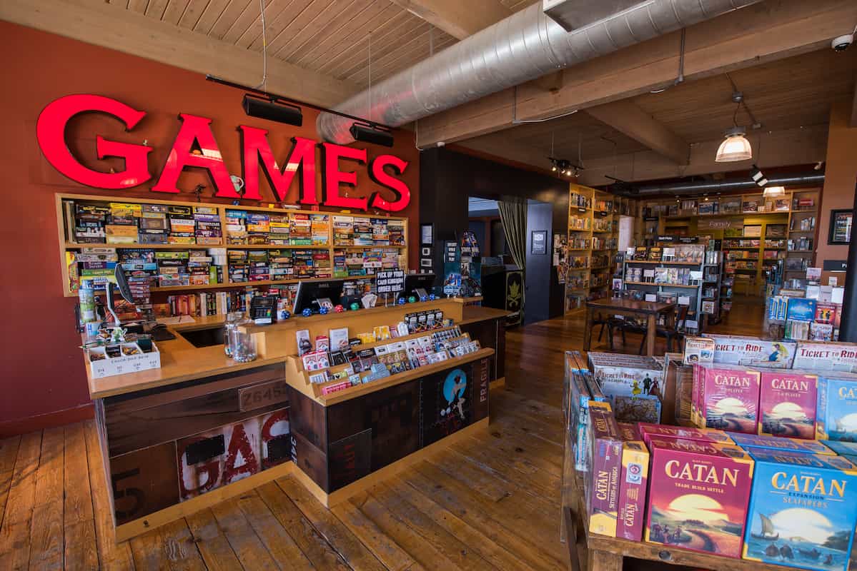 Mox Seattle board game store showing games of Catan on a table, the game library and large games sign over the register
