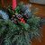 Closeup of tabletop centerpiece made with fresh greens and pinecones in a living room on coffee table. Red candle included.