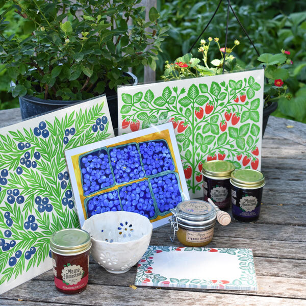 berry themed posters, jam jars and other items on a picnic table