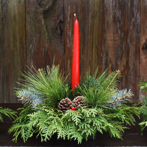 centerpiece made of natural greens with a red candle in the center