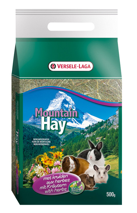 Green bag of Versele Laga Mountain Hay with herbs, featuring a mountain scene, hay, and small animals.