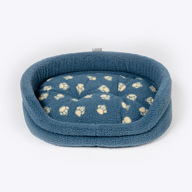 Blue sherpa fleece dog bed with paw print pattern, oval shape. Danish Design label.
