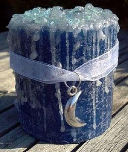 Blue Moon Candle, a large blue candle with a textured surface and a crescent moon pendant necklace wrapped around it.