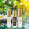 Kuumba Made Tropical Dreams Collection - 3 assorted fragrance oils, 0.15 oz each, in small bottles with gold caps and labels featuring flavors like Pikake Lei, Creamy Coconut, and White Ginger, placed outdoors with a blurred green and yellow background.