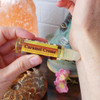 Shadow Scents Caramel Creme Perfume Oil - 1/3 oz. roll-on, a small transparent bottle with a yellow label and red text, being applied to a person's forearm.