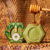 Baudelaire Calendula Honey Soap - 3.5 oz., green honeycomb-shaped soap with honey dripping on top and a honey dipper, accompanied by packaging with floral and honeycomb design.