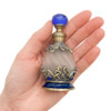 Uncommon Scents #7 Green Perfume Bottle - 15ml Round, ornate vintage-style perfume bottle with brass and blue accents, held in a person's hand.