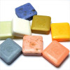 La Lavande 25g Guest Soap, collection of colorful square soap bars including blue, white, green, yellow, pink, gray, and peach, embossed with a floral design.
