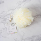 Urbana Spa Prive Body Buffer, luxurious white body buffer sponge on a marble surface with a tag attached.