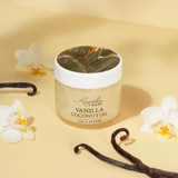 Kuumba Made Vanilla Coconut Oil - 2 oz., glass jar of vanilla coconut oil with vanilla beans and orchid flowers around it, on a beige background.