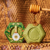 Baudelaire Calendula Honey Soap - 3.5 oz., green honeycomb-shaped soap with honey dripping on top and a honey dipper, accompanied by packaging with floral and honeycomb design.