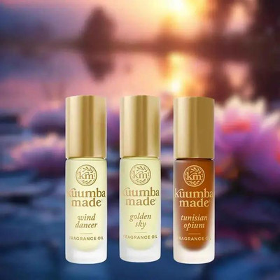 Kuumba Made Exotic Elegance Collection - 3 assorted 0.15 oz fragrance oils, image of small bottles with gold caps against a colorful, blurred sunset background.
