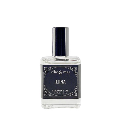 Ollie + Max Luna Perfume Oil - 1/2 oz., Clear glass bottle with dark blue label and black cap, containing fragrant oil for personal use.