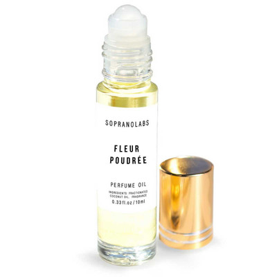 Soprano Labs FLEUR POUDRÉE Vegan Perfume Oil - 1/3 oz. roll-top, transparent glass bottle with a white label featuring black text, accompanied by a golden cap placed beside it.