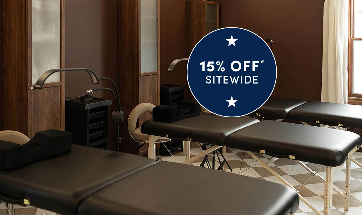 Spa and esthetician room showing line of black massage and facial tables with beige stools in a spa