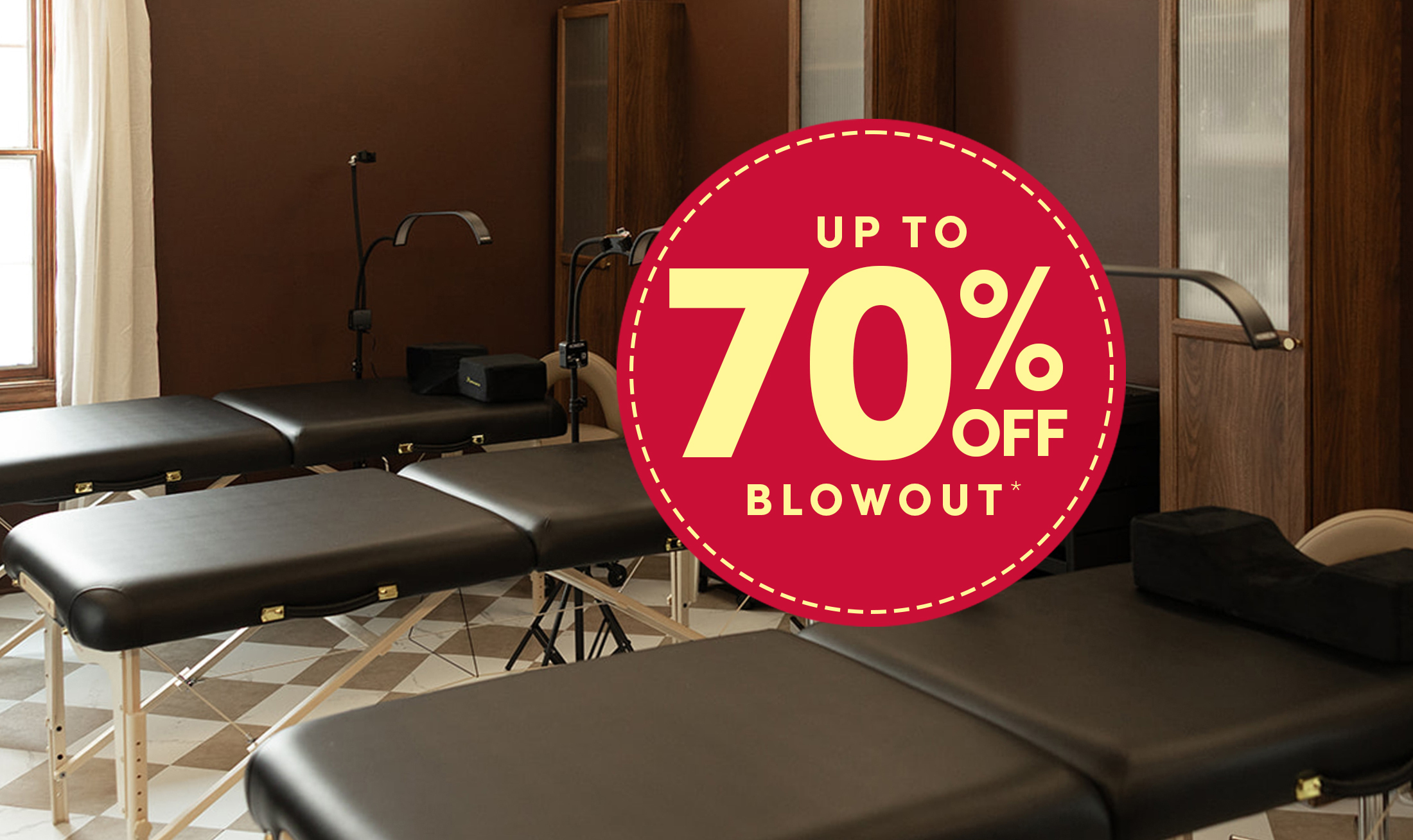 Spa and esthetician room showing line of black massage and facial tables with beige stools in a spa