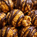 Close-up macro texture of handcrafted copper-kettle caramel popcorn glazed in melted ribbons of rich dark chocolate.