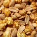 Close-up macro texture of Colette's Caramel Popcorn with Peanuts, showing roasted salted Virginia peanuts layered over glossy copper kettle caramel popcorn.