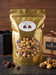 A flawless, perfectly smooth metallic gold stand-up pouch of scratch-made Chocolate Drizzled Caramel Popcorn. The precise label text 'Chocolate Drizzled Caramel' and the two distinct chocolate block graphics are visible on a sharp white circular sticker. A large clear window reveals the appetizing, detailed mix of caramel popcorn kernels heavily coated with rich dark chocolate drizzles. The bag is centered in a pristine, neutral professional studio environment, completely free of any popcorn tins