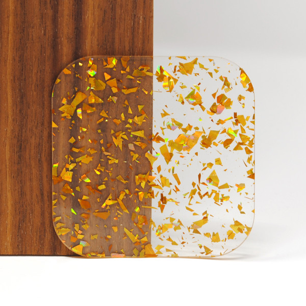 Gold Confetti acrylic sheet ??? 3mm clear cast acrylic with vibrant gold foil flakes, laser-compatible for Glowforge and xTool, ideal for crafts, jewelry, and signage. Sample shown against wood and white background.